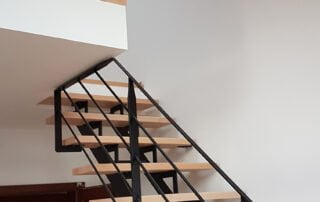 Moderní schodiště s kovovým zábradlím Zakázkové interiérové schodiště s dřevěnými stupni a designovým černým kovovým zábradlím z naší realizace.