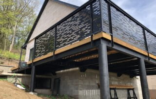 Ocelová terasa s perforovaným zábradlím Ocelová terasa na pilířích s moderním perforovaným kovovým zábradlím a dřevěnou podlahou, realizace KOVKOM.