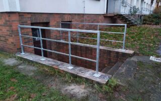 Kovové zábradlí sklepního vstupu Nové kovové zábradlí pro bezpečný vstup do sklepa bytového domu. Zakázková výroba a montáž KOVKOM.