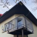 Nově instalovaný kovový závěsný balkon s černým zábradlím na fasádě rodinné vily, zakázková výroba KOVKOM.