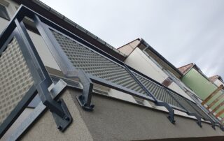 Balkonové zábradlí z tmavého kovu s moderní tahokovovou výplní, zakázková kovovýroba KOVKOM.