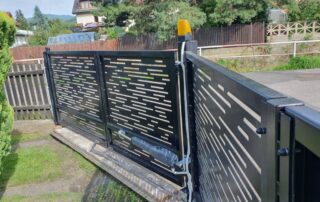 Moderní černá posuvná brána s designovou perforovanou výplní a automatickým pohonem pro vjezd do nemovitosti