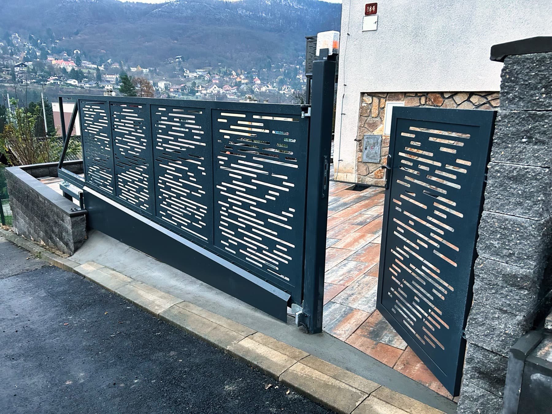 Oplocení a samonosná pojezdová brána s brankou v CNC designu, antracit, řešení svahu